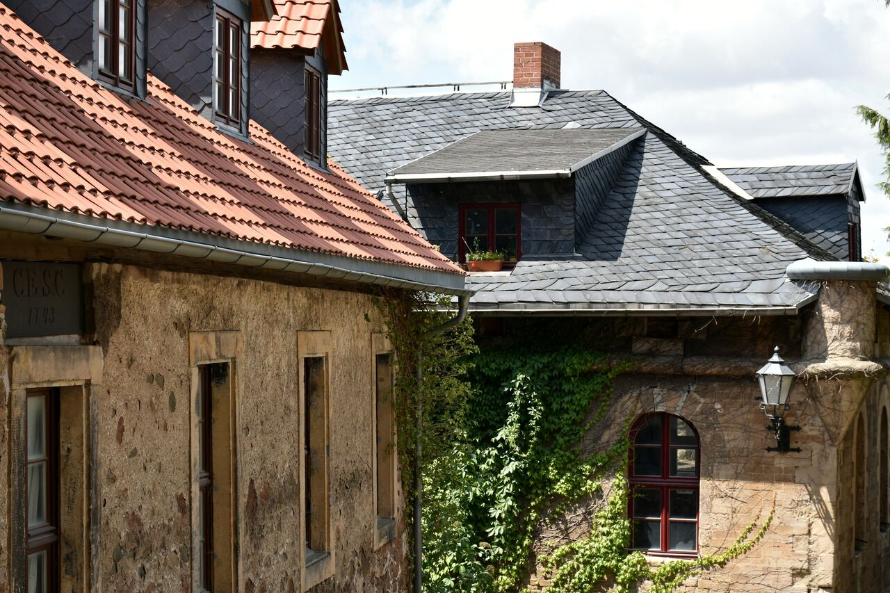 Maisons anciennes aux murs en pierre : toitures en tuiles et en ardoises, lucarne et gouttières en zinc.